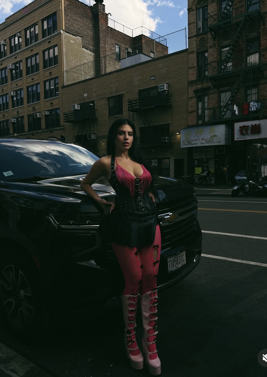 Bina The Foreign posing on a city street in front of a black SUV