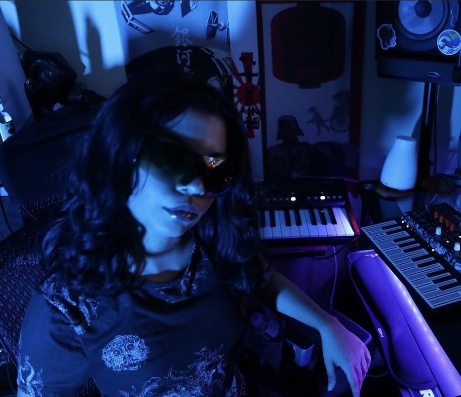 LŸDIA wearing sunglasses in a music studio under blue lighting