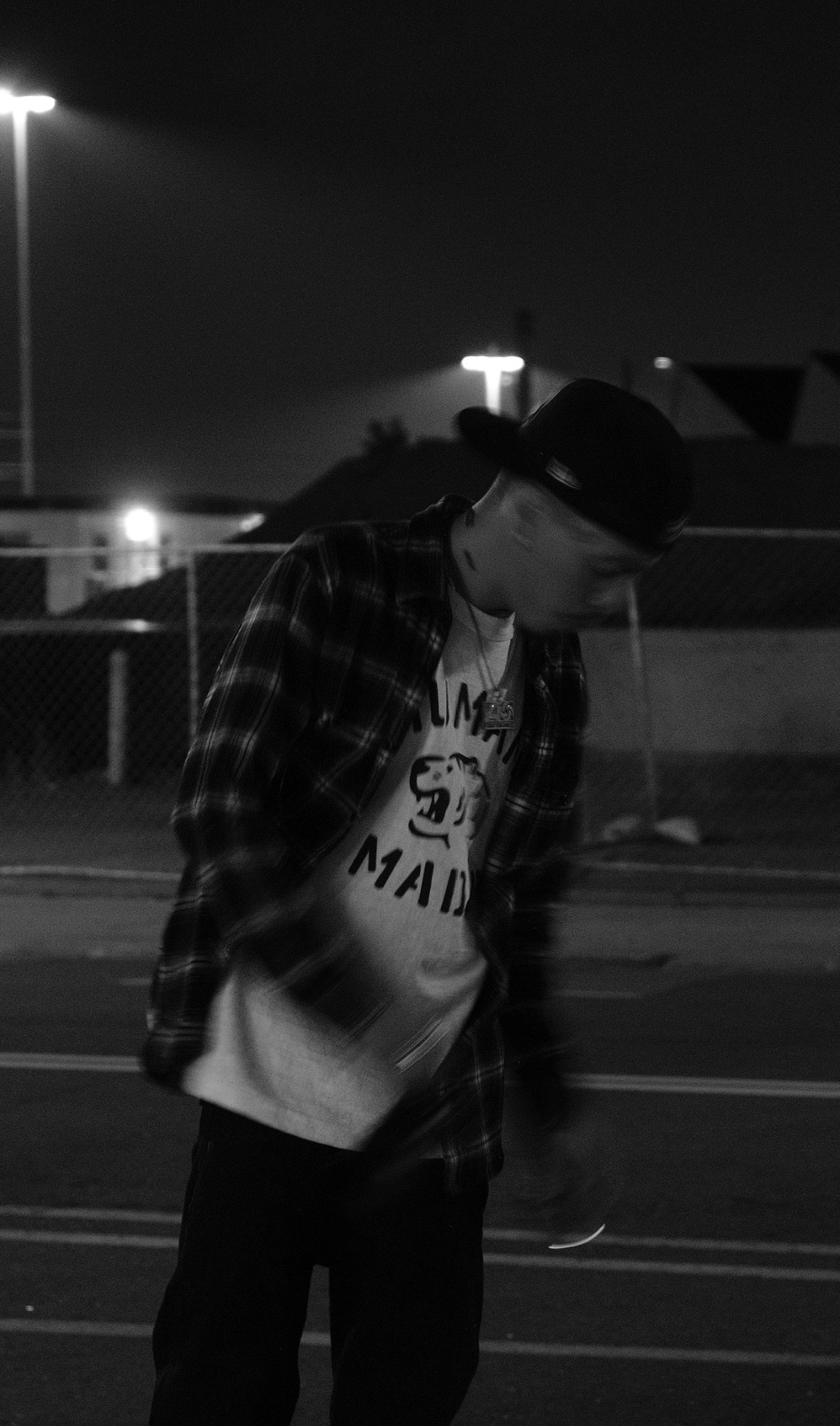 where.t.at wearing a cap and plaid shirt outdoors at night, photographed in black and white